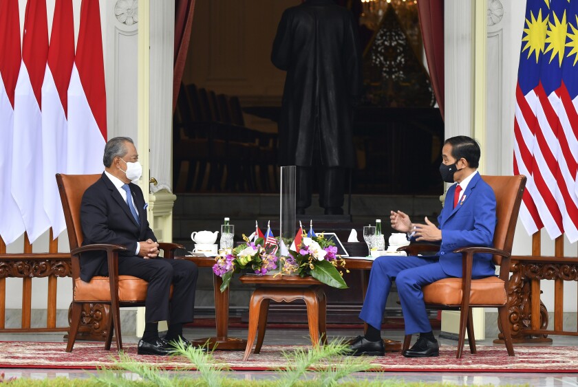 In this photo released by Indonesian Presidential Palace, Malaysian Prime Minister Muhyiddin Yassin, left, talks with Indonesian President Joko Widodo during their meeting at Merdeka Palace in Jakarta, Indonesia, Friday, Feb. 5, 2021. Yassin is currently on a two-day visit in the country. (Agus Suparto, Indonesian President Palace via AP)