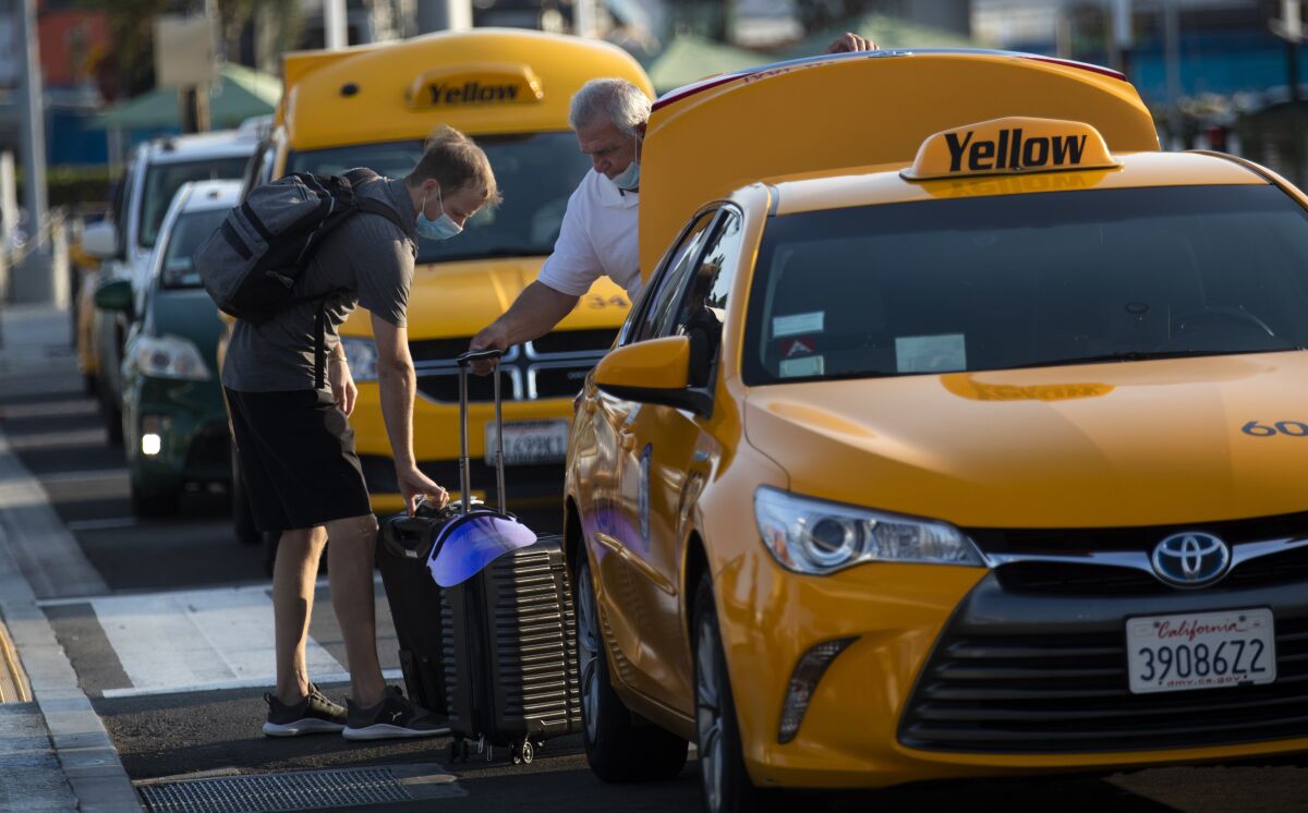 A taxi driver helps a passenger with luggage at LAX.
