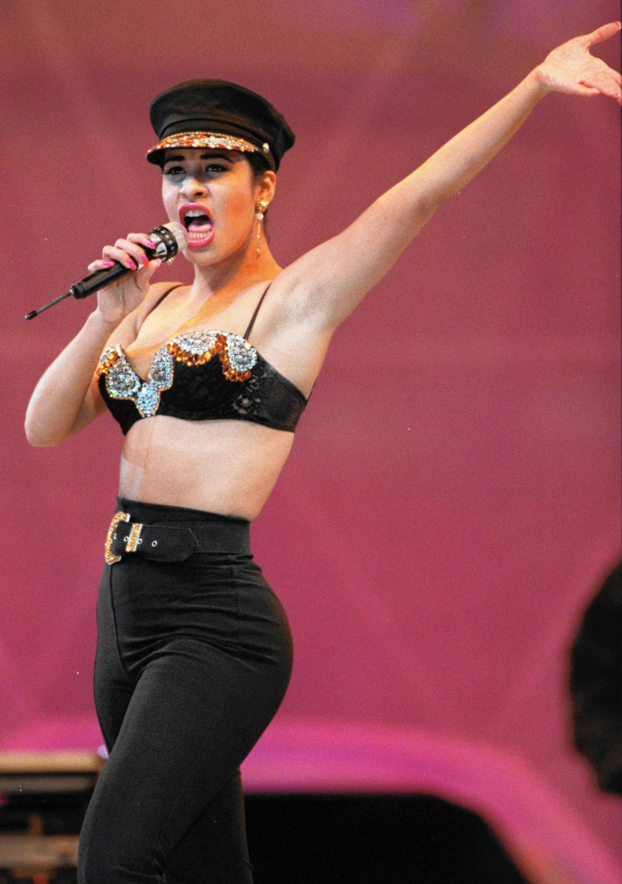 In blinged-out military-style hat and bikini top, Tejano music star Selena performs in 1993. 