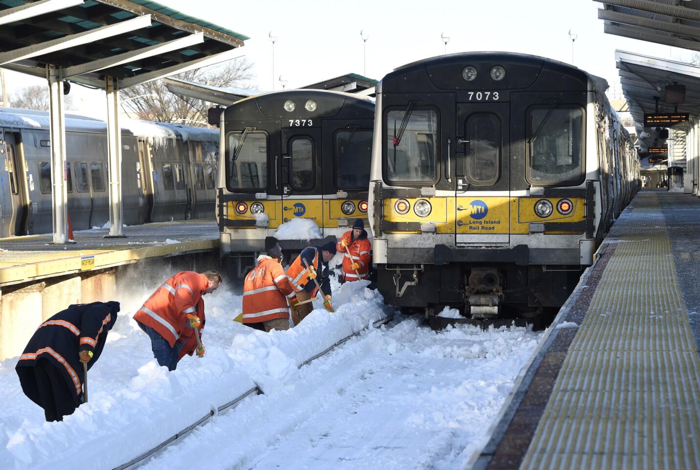 Workers clear the tracks of snow at the Port Washington branch of the Long Island Railroad Monday, Jan. 25, 2016 in Port Washington, N.Y.