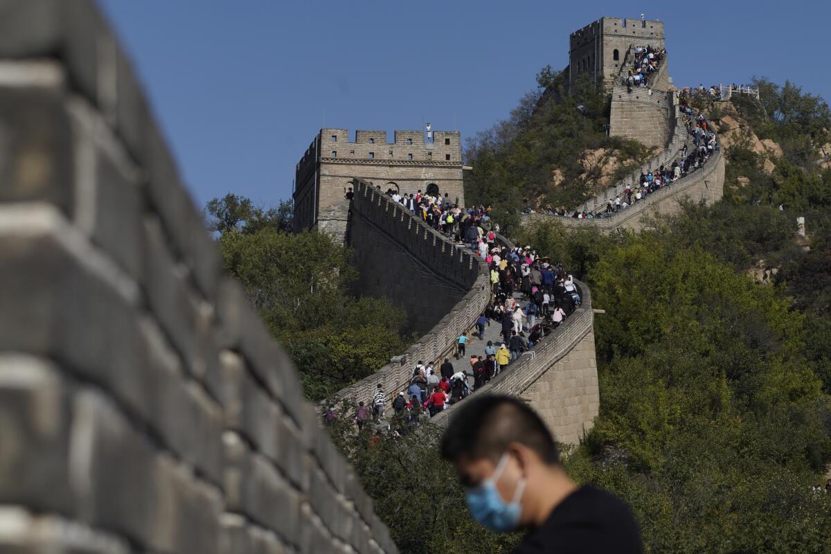 Un hombre con mascarilla, para protegerse del coronavirus, cerca de un tramo de la Gran Muralla China