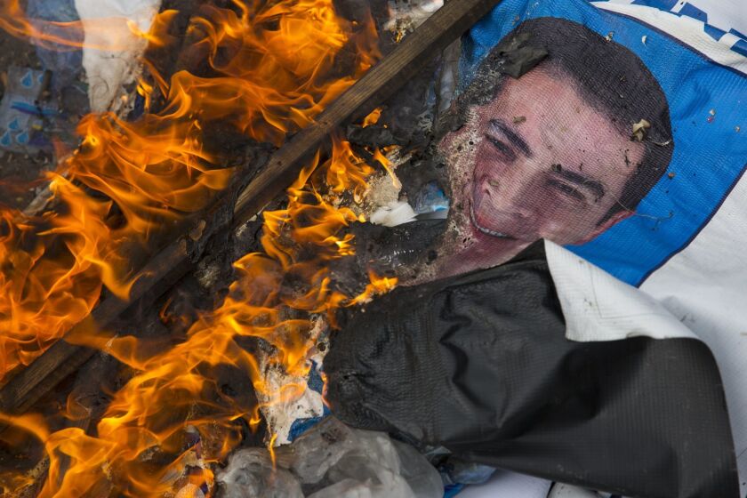 A campaign poster of Honduran President Juan Orlando Hernandez, who's running for reelection, burns after being set on fire by supporters of his rival, candidate Salvador Nasralla, during a protest against what they call electoral fraud in Tegucigalpa, Honduras.