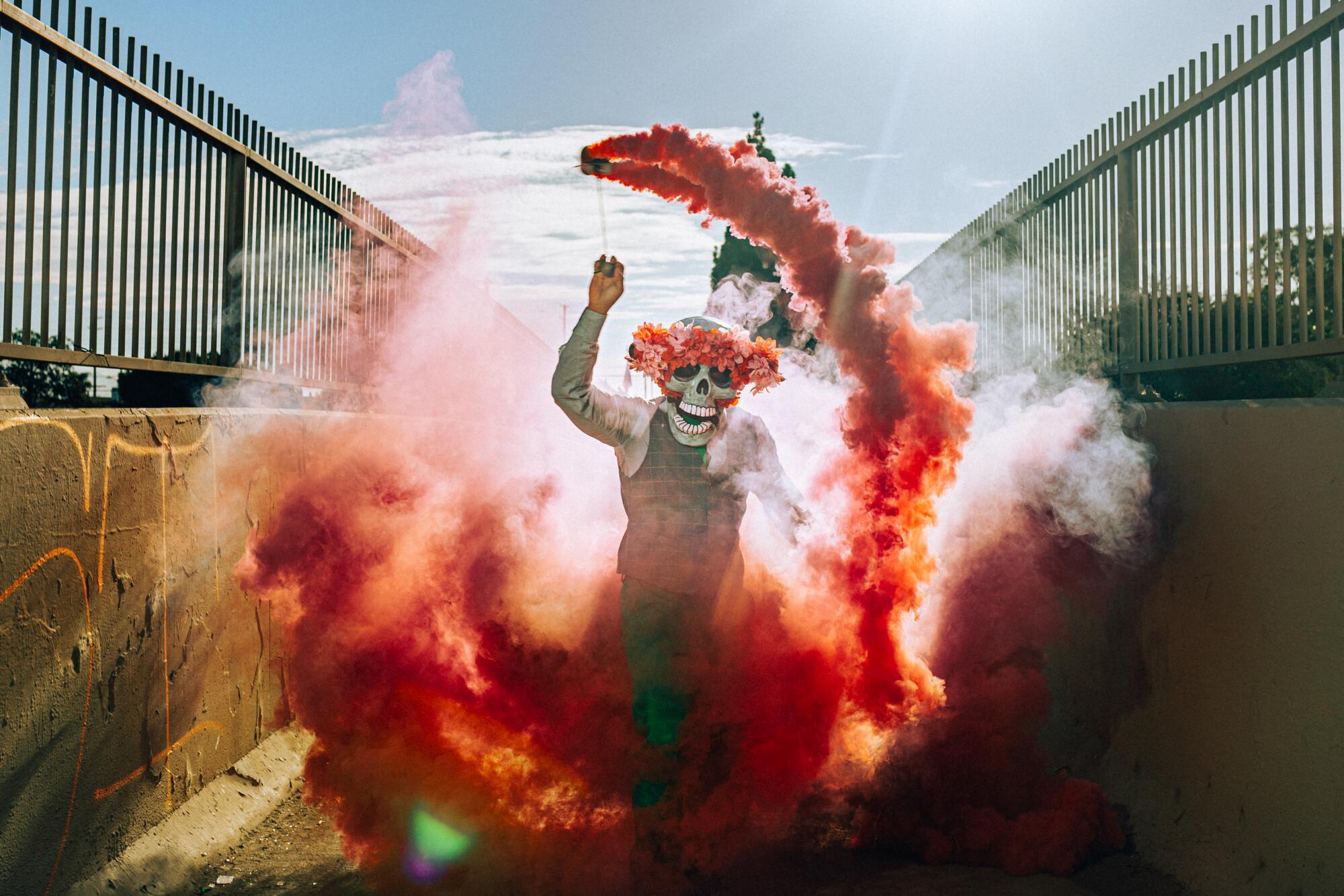 A man wearing a skull mask, surrounded by red smoke.