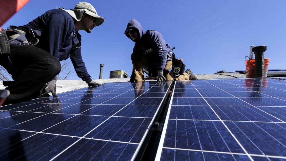 George Gonzalez, left, and Hector Maldonado, install a solar system on home in Van Nuys in 2016. Higher temperatures and more air conditioning will increase peak electricity demand, according to California's latest climate assessment.