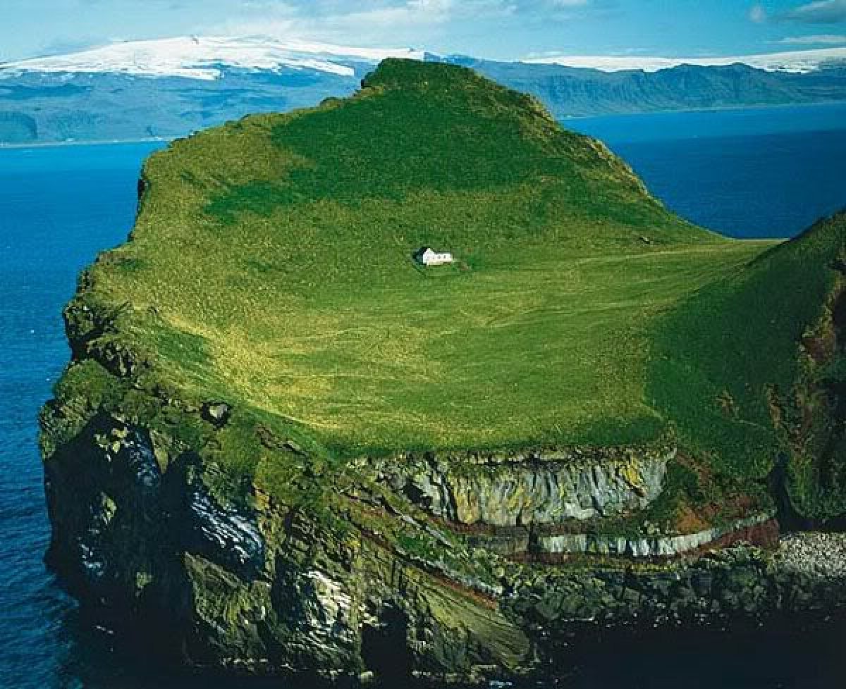 Iceland's Vestmannaeyjar Archipelago includes grassy islands that sometimes feature solitary cabins.