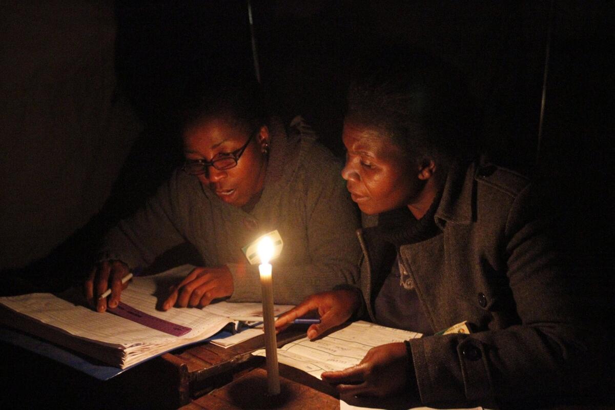 Zimbabwe Electoral Commission officers check through a voter roll before balloting closed in Harare on Wednesday.