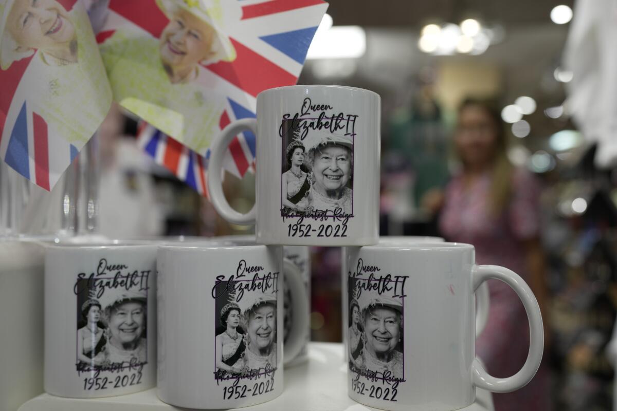Mugs with print of Queen Elizabeth II are displayed for sale at a gift shop in London, Monday, Sept. 12, 2022. Just days after the death of Queen Elizabeth II, unofficial souvenirs have rolled out at royal-themed gift shops in London and online marketplaces like Amazon and Etsy. (AP Photo/Kin Cheung)