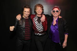 Ronnie Wood, left, wears a red and black shirt and a leather jacket, Mick Jagger, center, wears a black 