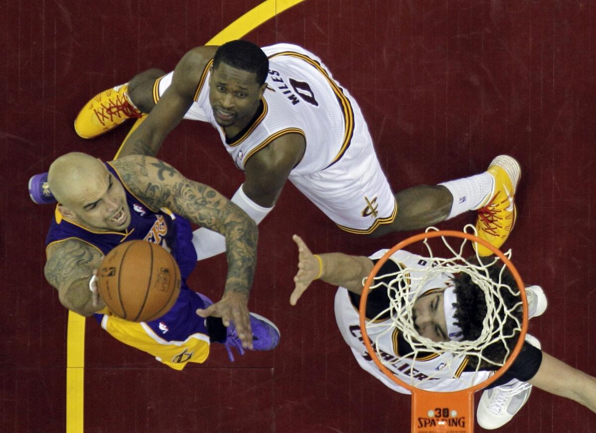 Lakers center Robert Sacre tries to score inside against Cavaliers forward C.J. Miles and center Anderson Varejao in the second half of a game against Cleveland on Feb. 5