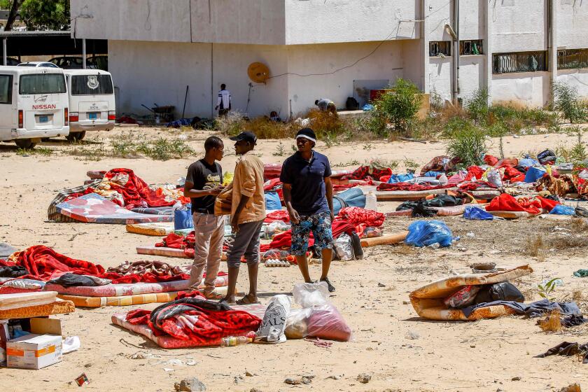TOPSHOT - Migrants stand and walk outside at a detention centre used by the Libyan Government of National Accord (GNA) in the capital Tripoli's southern suburb of Tajoura on July 3, 2019, following an air strike on a nearby building that left dozens killed the previous night. - Over 40 migrants were killed in an air strike early late on July 2 on their detention centre in a Tripoli suburb blamed on Libyan strongman Khalifa Haftar, who has been trying for three months to seize the capital. The UN said the air strike "may amount to a war crime". More than 130 people were also wounded in the in the raid on Tajoura, the statement added. (Photo by Mahmud TURKIA / AFP)MAHMUD TURKIA/AFP/Getty Images ** OUTS - ELSENT, FPG, CM - OUTS * NM, PH, VA if sourced by CT, LA or MoD **