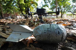 A close-up of an improvised bomb and a drone at rest among leaves on the ground
