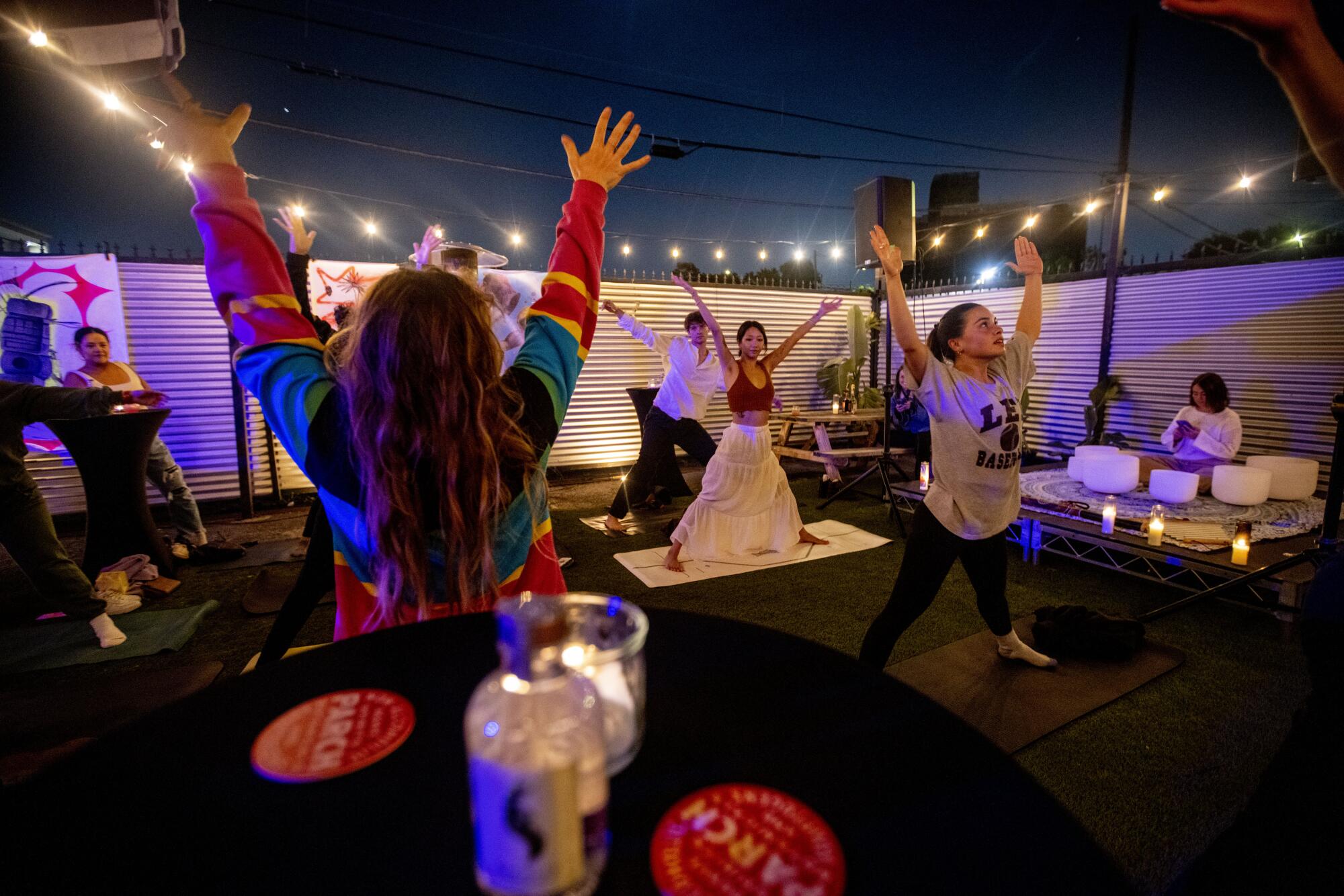 People do yoga under string lights at night.