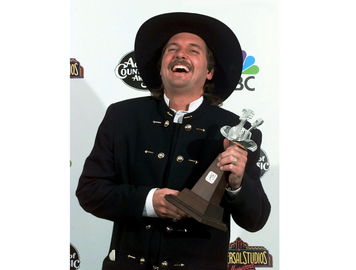 Jeff Carson holds an award and smiles.