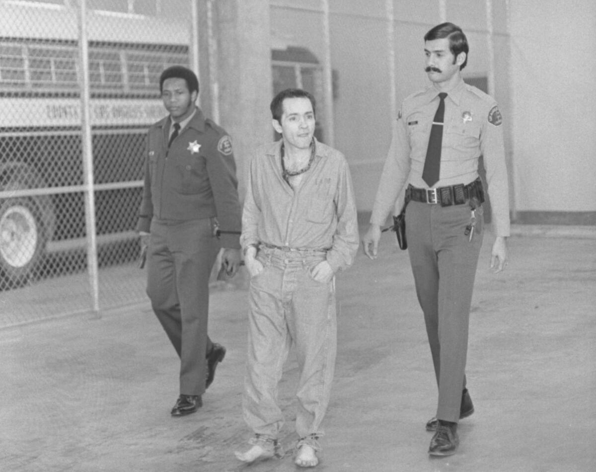Charles Manson is escorted by two sheriffs 