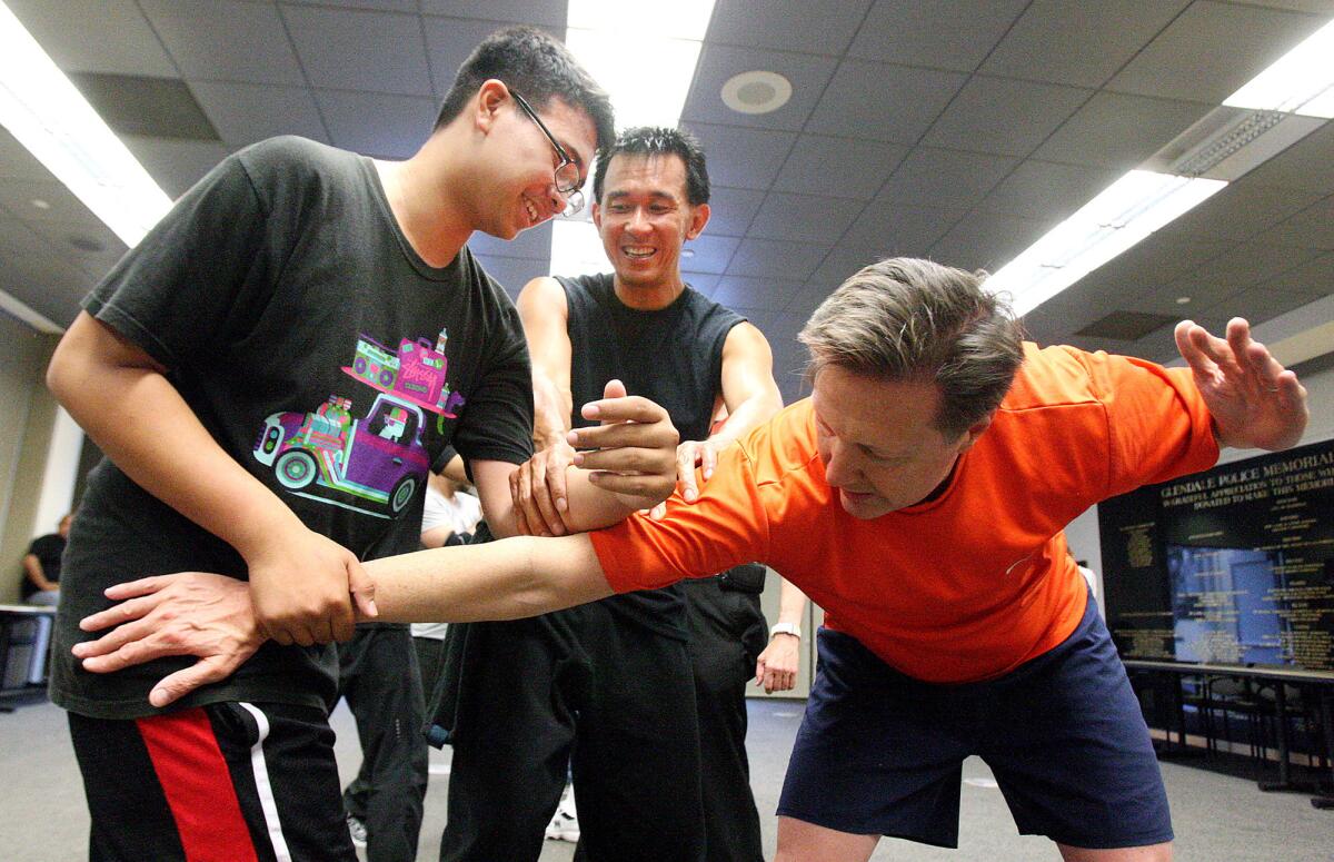 With the assistance of instructor Nelson Nio, Russell Muñoz, 13, of Glendale, strikes the vulnerable arm of Gary Gausman, of Glendale, in a first-time, one-off men's self-defense class at the Glendale Police Department on Wednesday, June 18, 2014. The class is in response to men asking for a class similar to women's self-defense classes.