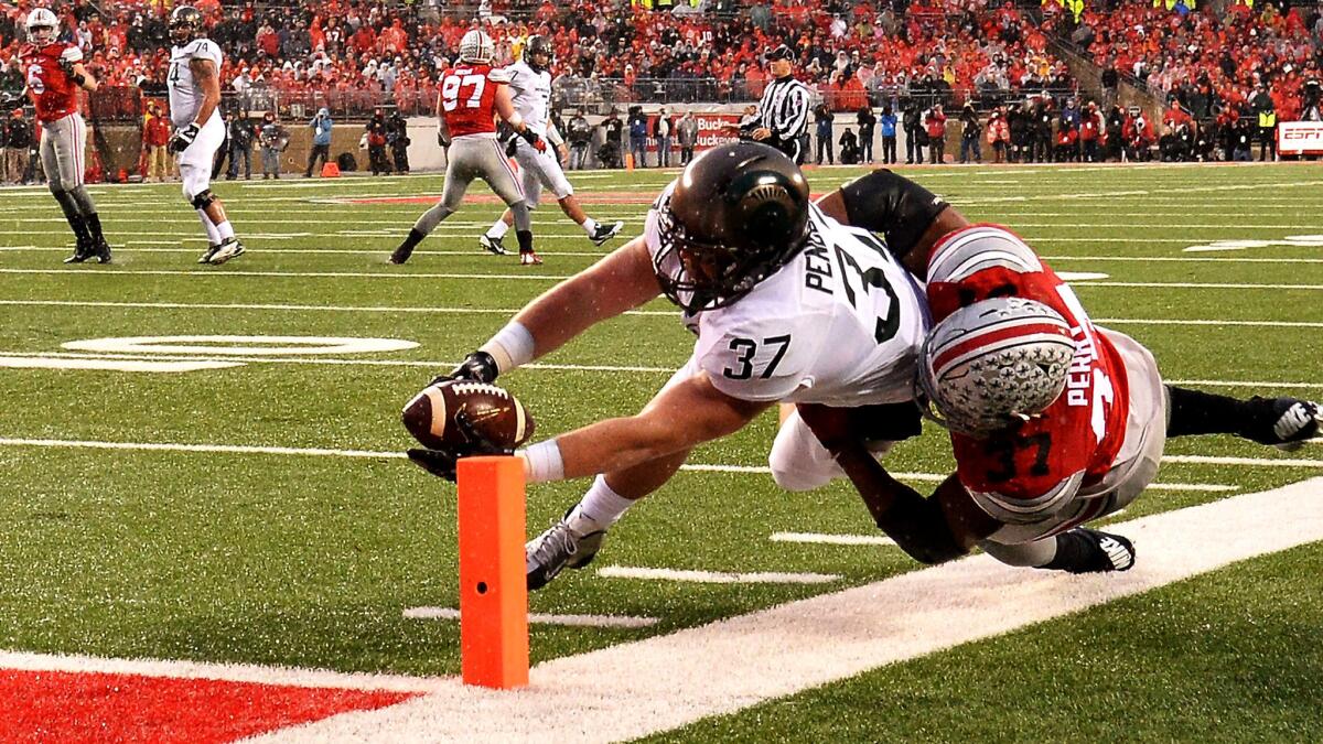 Michigan State fullback Trevon Pendleton gets the ball across the goal line despite the effort of Ohio State linebacker Joshau Perry for a touchdown Saturday.