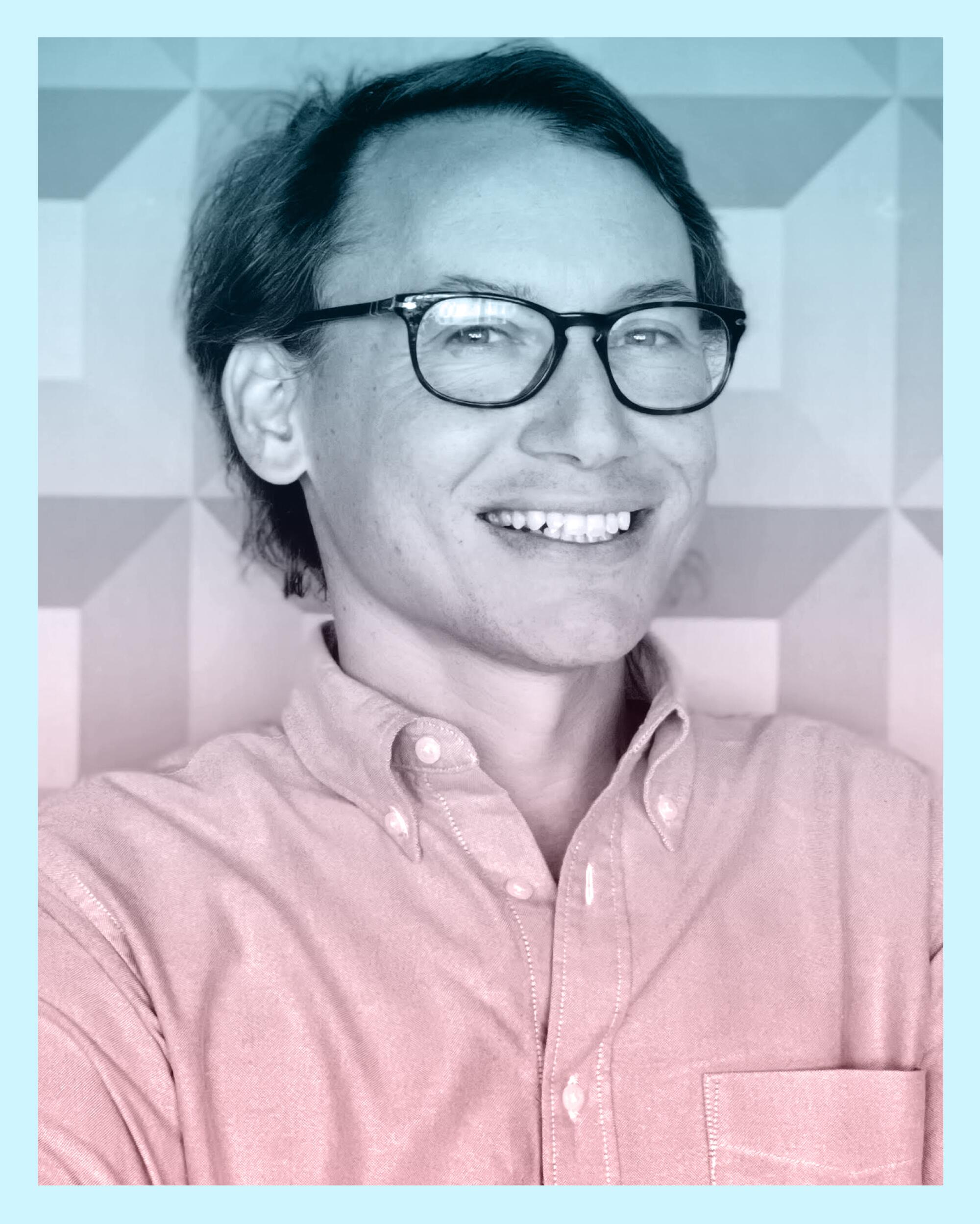 A smiling man in glasses and a button-down shirt