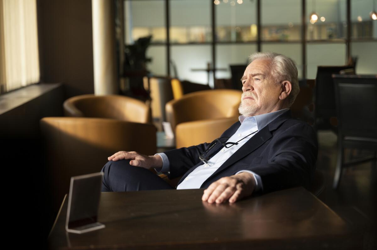 Brian Cox, as Logan Roy, sits in a lounge looking pensive.