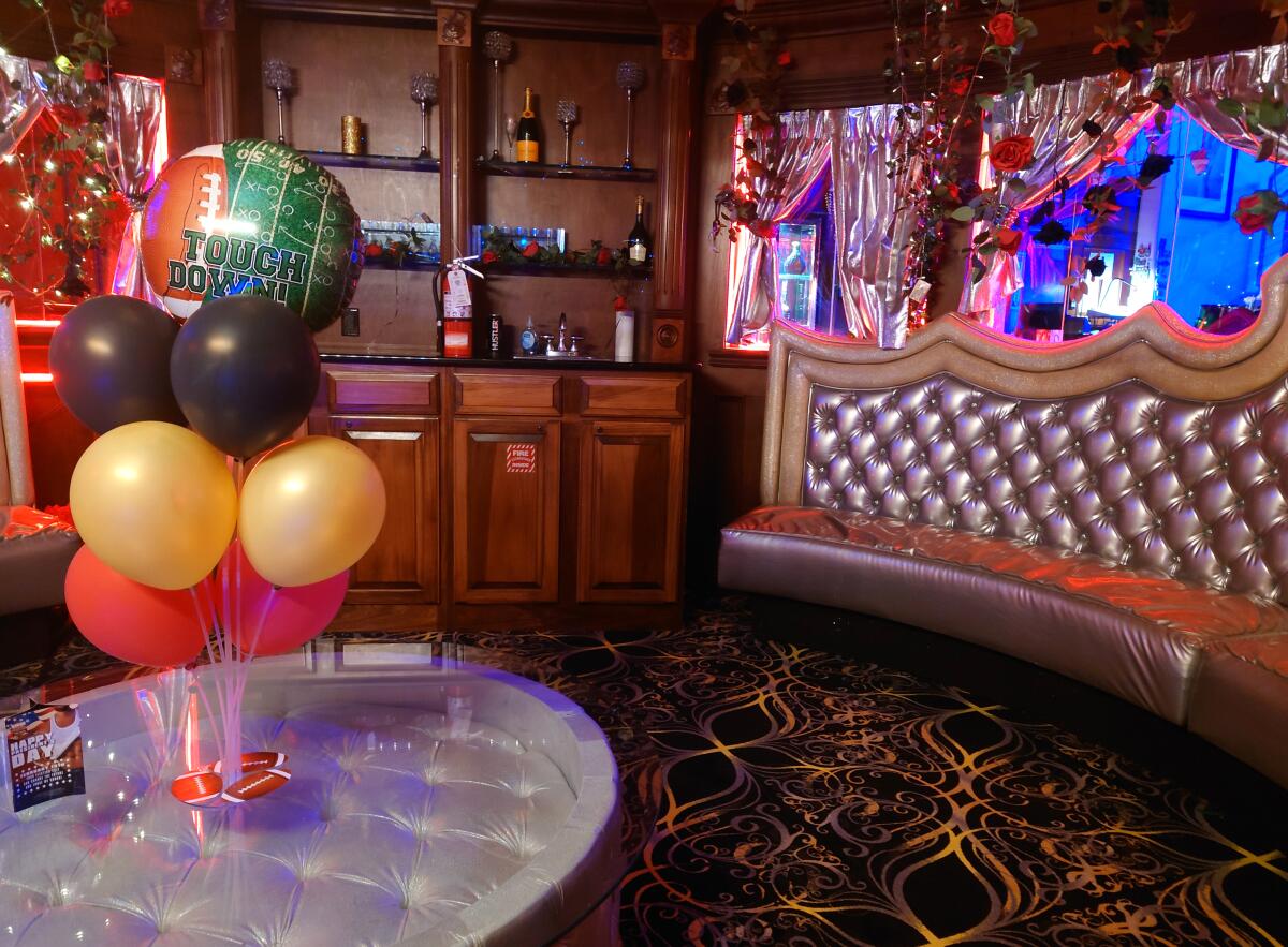 Balloons rest on a coffee table next to a tufted metallic couch in a Champagne room.