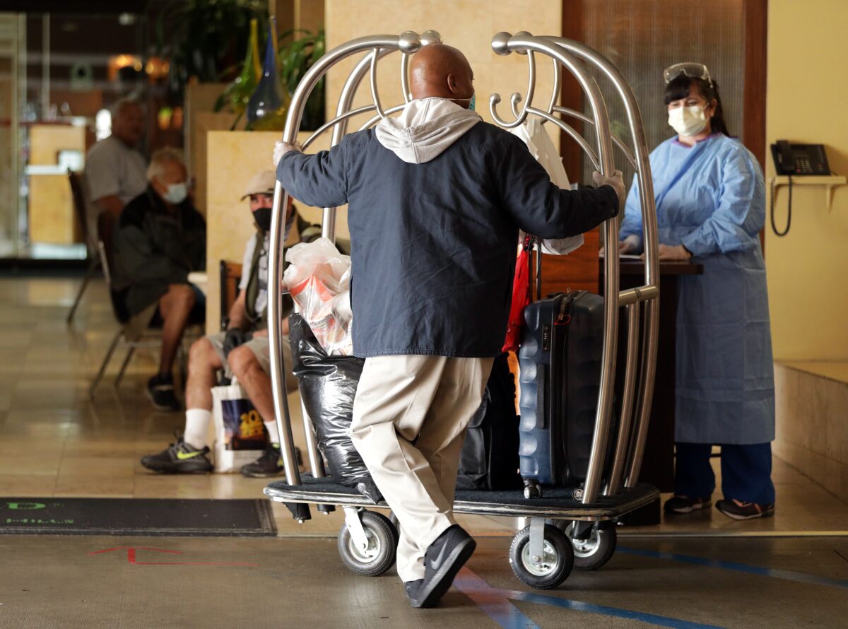 Omar Spry of Los Angeles Housing Community Investment Department, pushes a cart of residents' bags into a West L.A. hotel that has been turned into housing for homeless people during the coronavirus pandemic. 