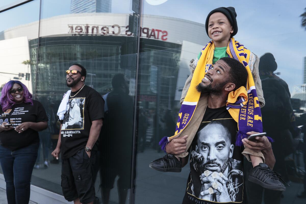 Demond Hewlitt Jr., in a T-shirt with Kobe Bryant's likeness, carries son Demond on his shoulders outside Staples Center.