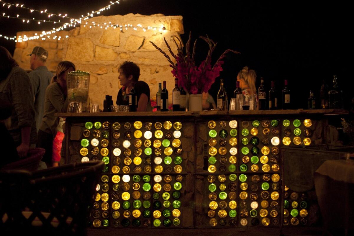 Wine bottles saved from past dinner parties were stacked with mortar to create the bar at the Ruin, Paul Goff and Tony Angelotti's alfresco spot for entertaining friends in Pipes Canyon.