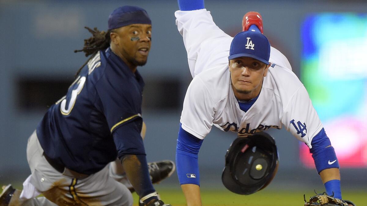 Dodgers shortstop Miguel Rojas, right, forces out Milwaukee's Rickie Weeks at second base while turning a double play in the Dodgers' loss Saturday.