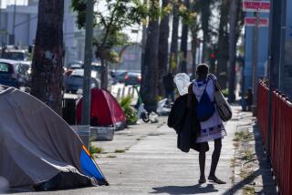 Hollywood, CA - August 15: A homeless woman walks with her belongings as Mayor Karen Bass' Inside Safe program employees along with the Los Angeles Sanitation Bureau clean up homeless encampments along Hollywood Blvd. and Gower Street on Thursday, Aug. 15, 2024 in Hollywood, CA. (Brian van der Brug / Los Angeles Times)