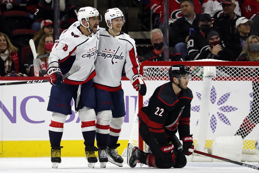 Washington Capitals' Alex Ovechkin (8) celebrates his goal with teammate Lars Eller (20) with Carolina Hurricanes' Brett Pesce (22) nearby during the second period of an NHL hockey game in Raleigh, N.C., Sunday, Nov. 28, 2021. (AP Photo/Karl B DeBlaker)