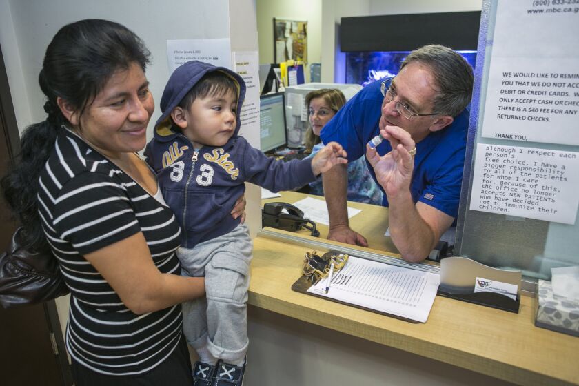 Northridge pediatrician Charles Goodman talks with Carmen Lopez, 37, holding her 18-month-old son, Daniel, after receiving the measles-mumps-rubella vaccine.
