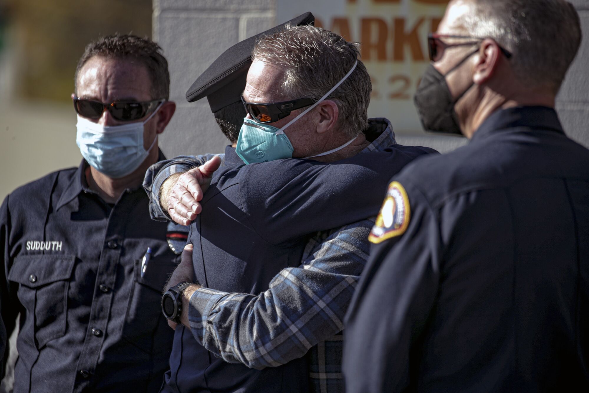 Two firefighters embrace while two others look on 