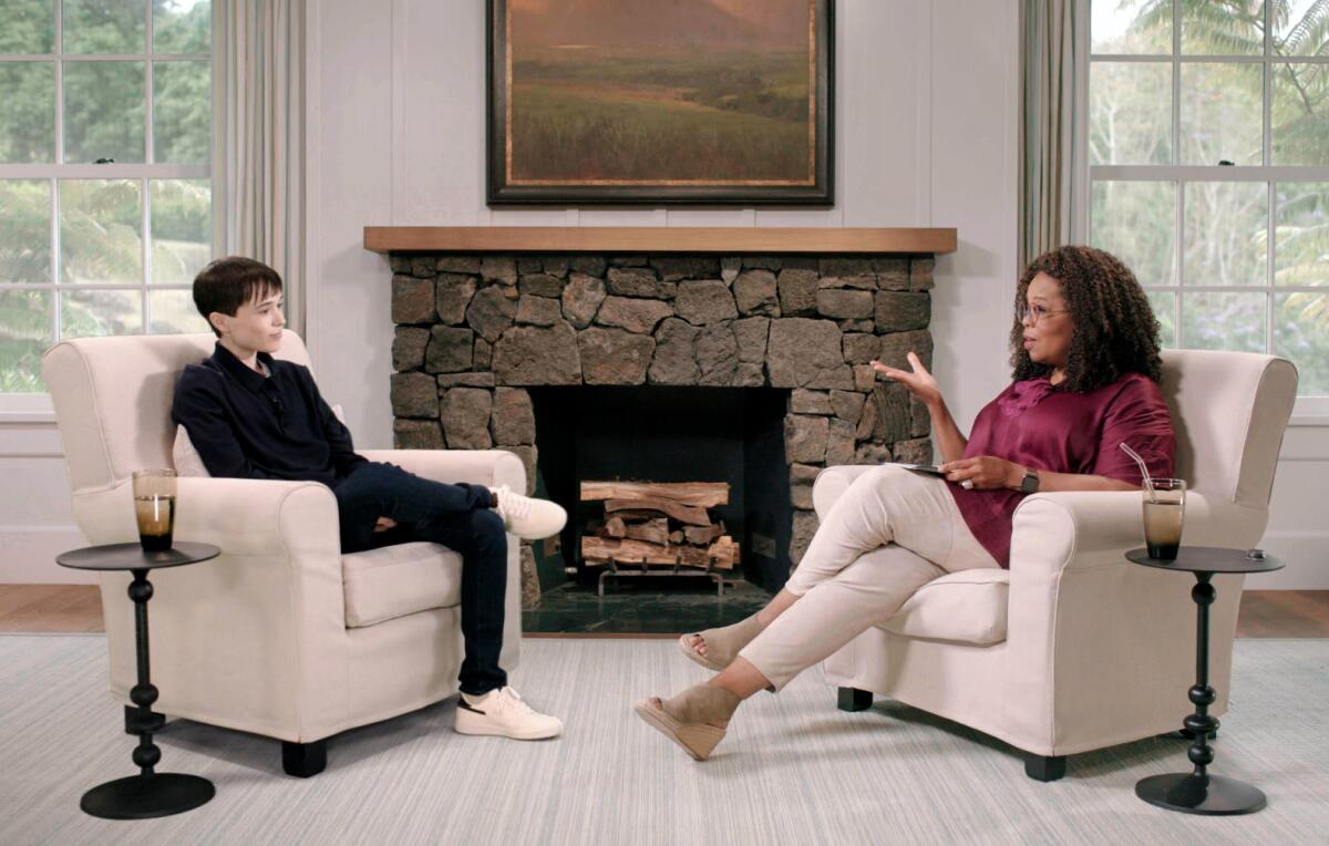 Elliot Page and Oprah Winfrey chat in living room armchairs.