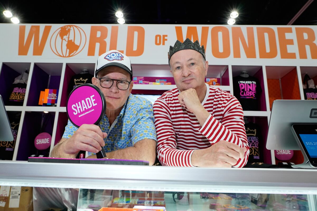 Two men posting at a merch booth