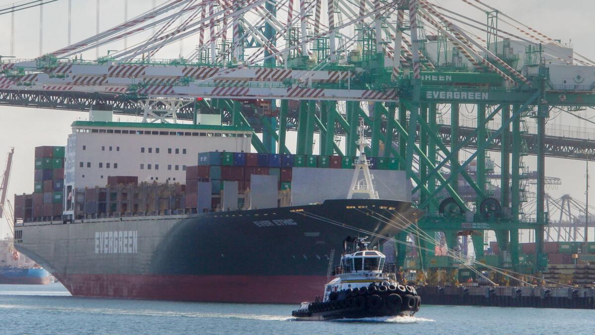A tugboat cruises past a container ship in the Port of Los Angeles in San Pedro on June 12.