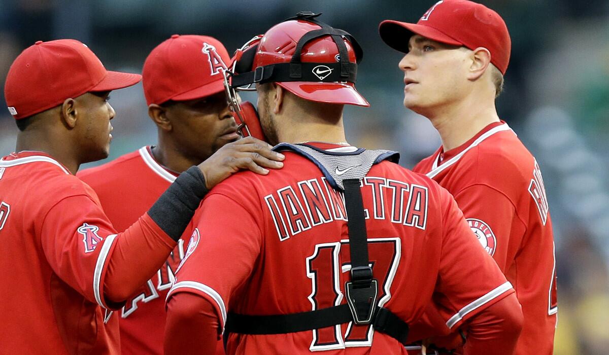 Angels starting pitcher Garrett Richards, right, is visited by catcher Chris Iannetta and infielders Howie Kendrick and Erick Aybar during a rough first inning against the A's on Friday night in Oakland.