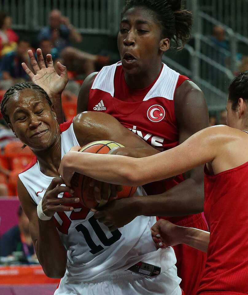Team USA's Tamika Catchings, left, wrestles the ball from Turkey's Kuanitra Hollingsvorth in the second half of a preliminary game at the London 2012 Olympics.