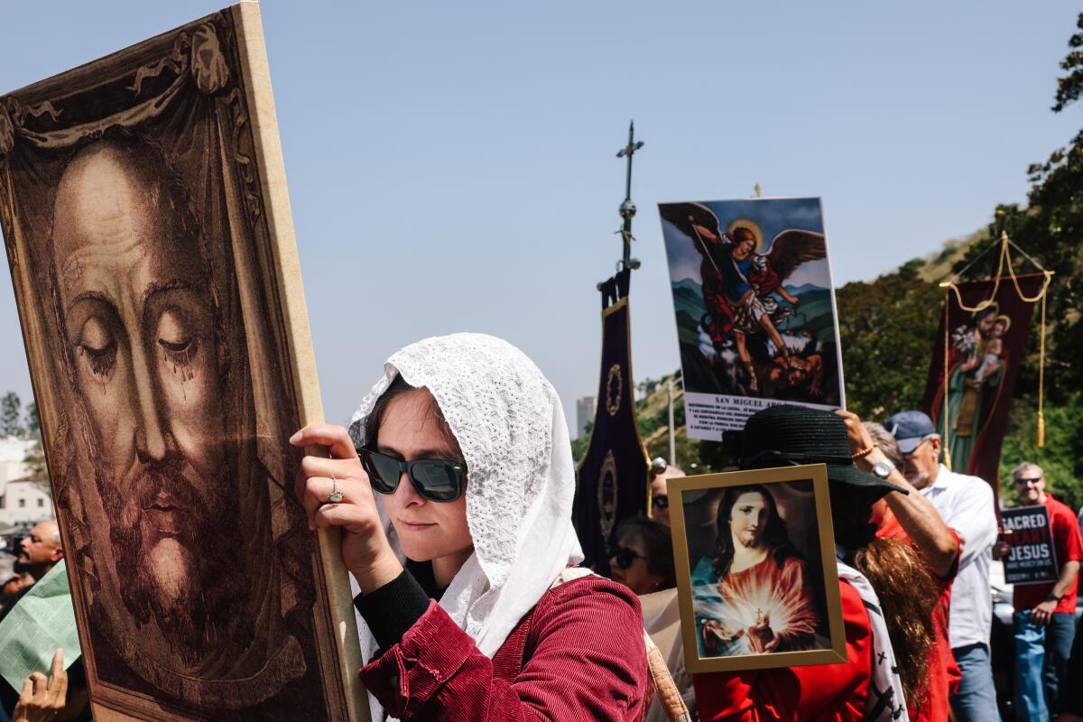 A crowd holds images of Jesus and crosses