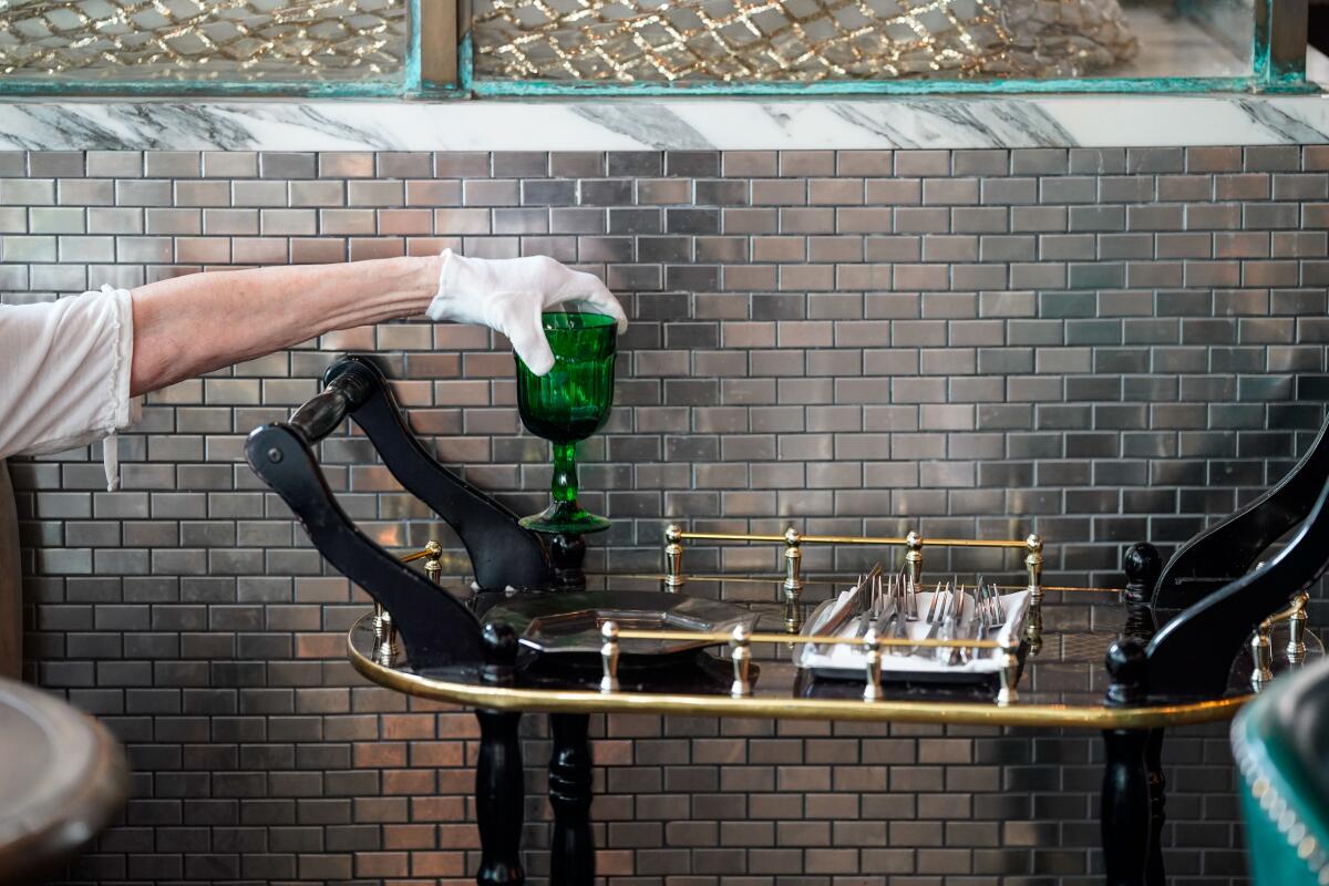 A worker reaches for a clean glass from the cart at Faith & Flower in downtown Los Angeles on June 6.