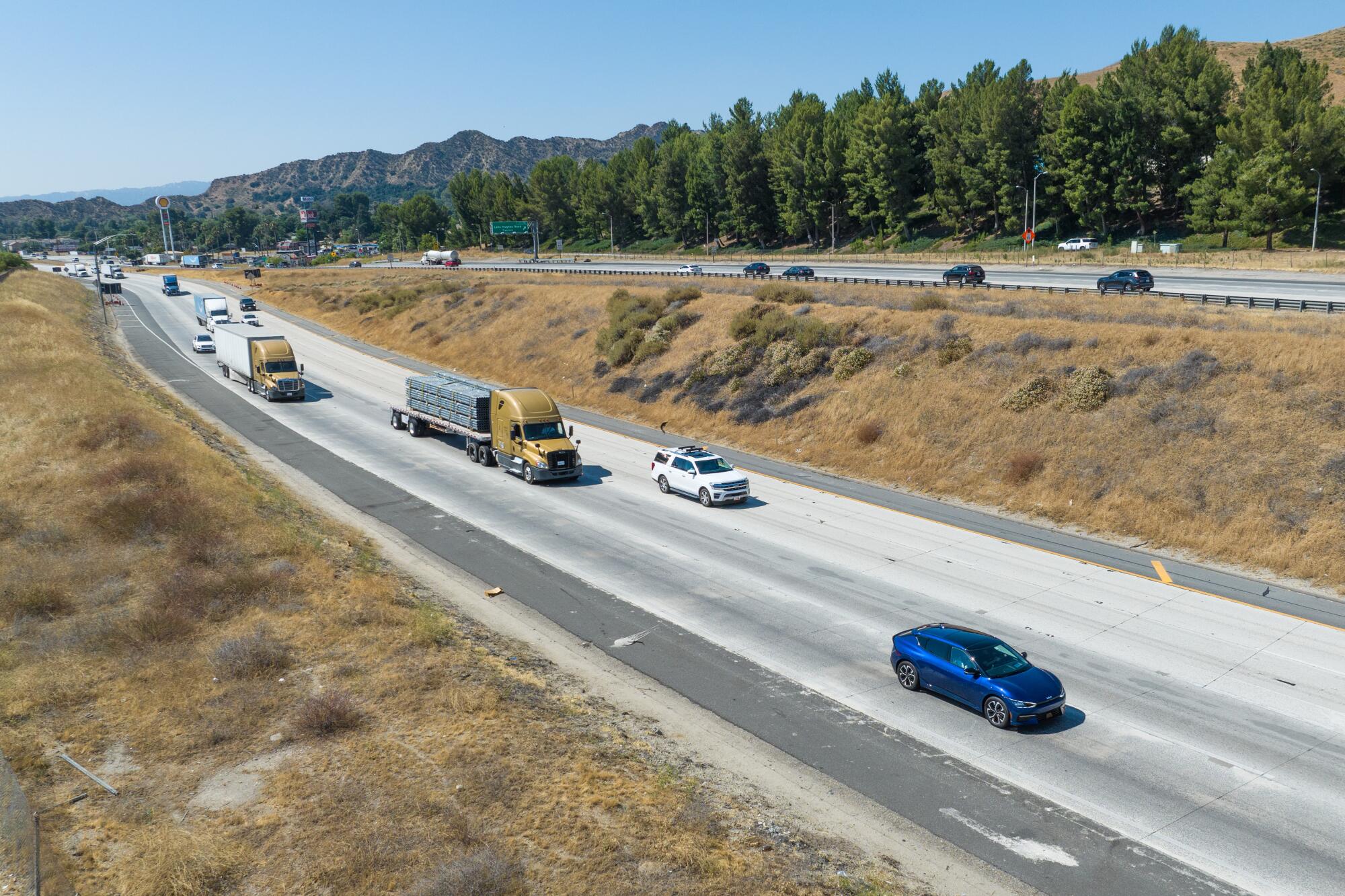 Cars and semi trucks roll along a rural freeway.