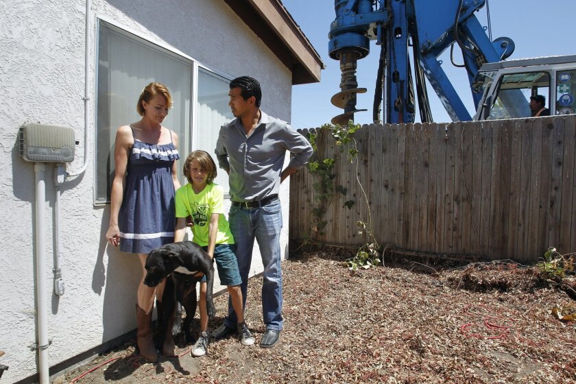 Leonardo Rios, Sarah Sokolow, Sokolow's son Vincent Sharp, 9, and their dog Miss Kay stand in the backyard of the home they rent as heavy machinery drills into the ground within feet of the master bedroom in North Park on Friday.