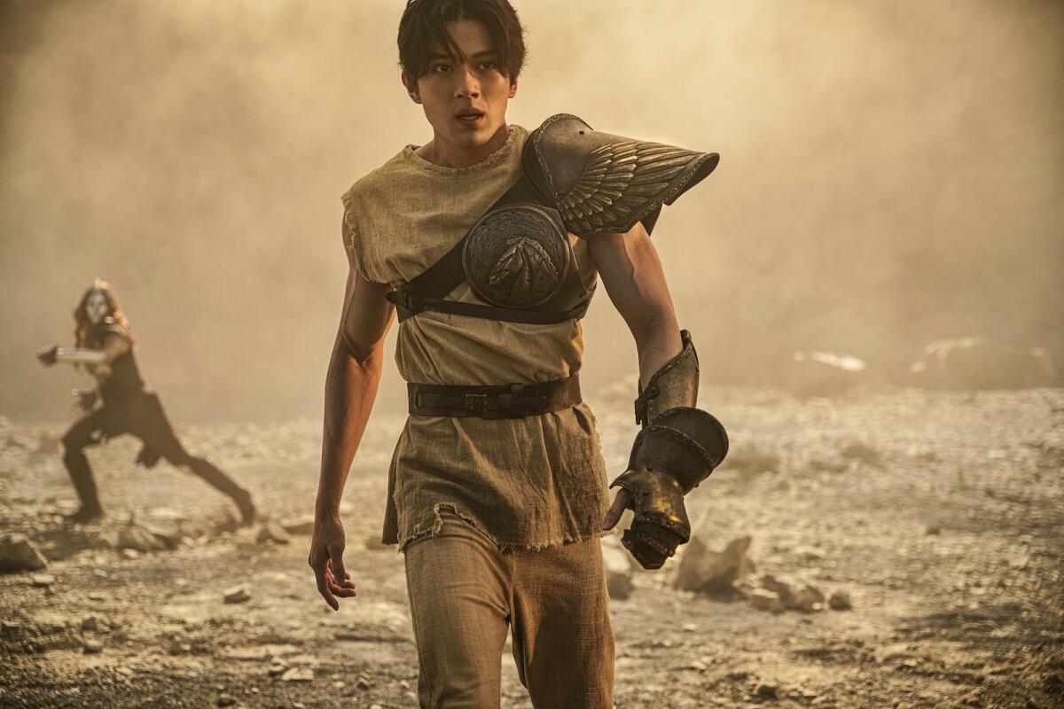 A man with one wing on a shoulder walks across a desolate landscape.