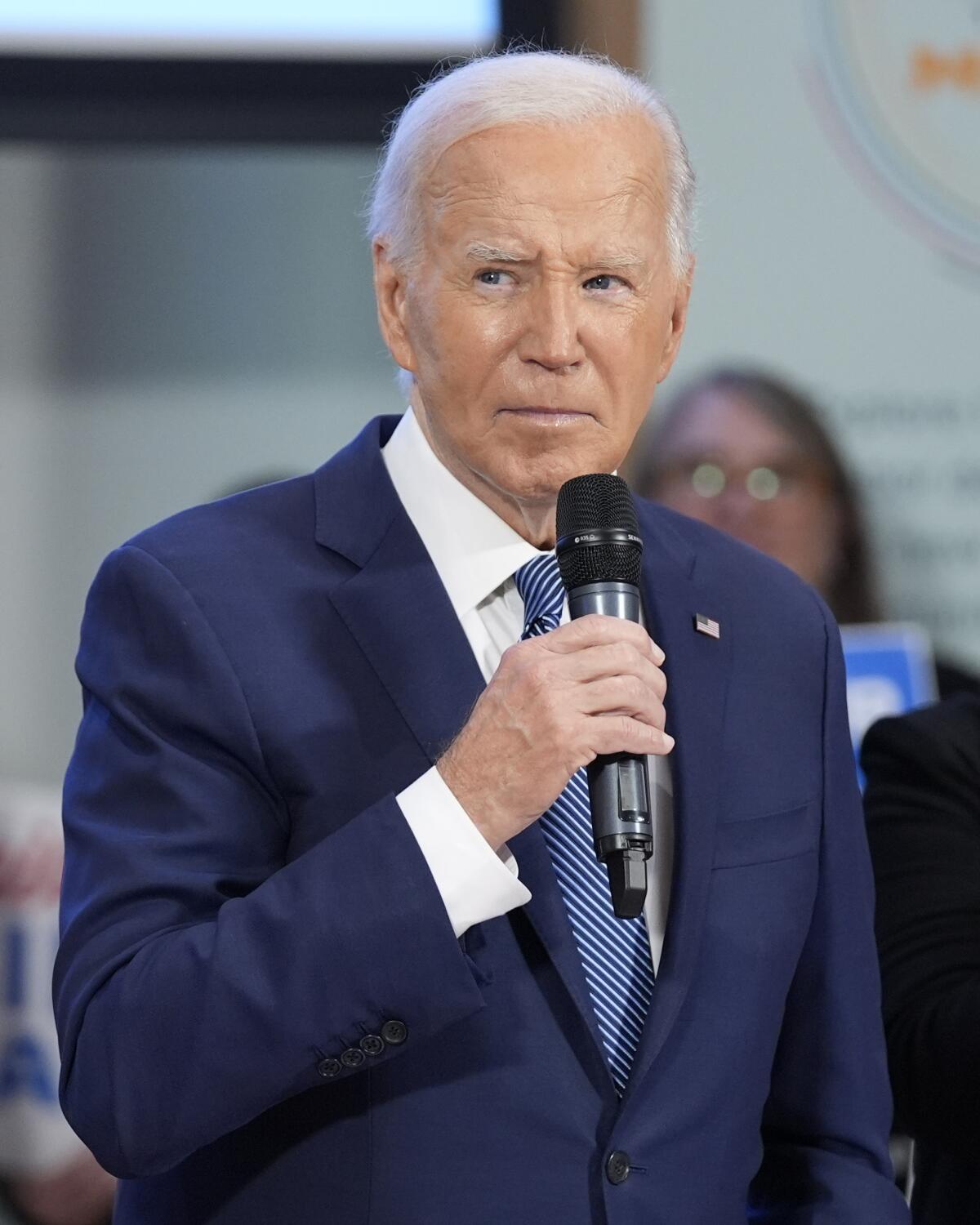 President Biden holds a microphone.