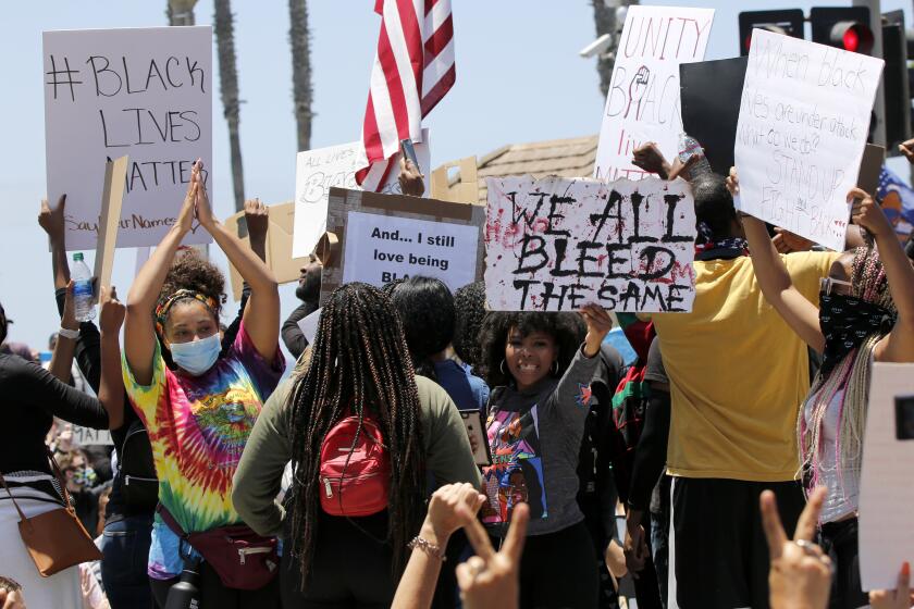 Protesters hold up signs during a Black Lives Matter protest in Huntington Beach on Saturday.