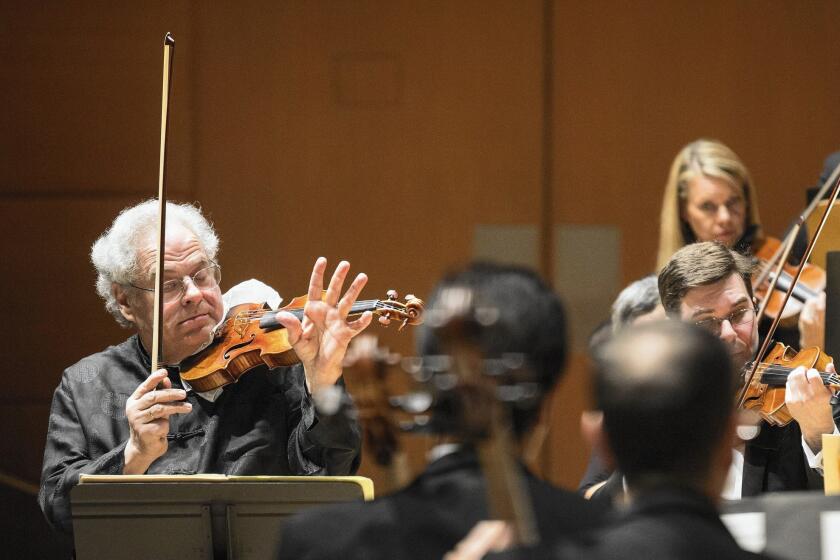 Itzhak Perlman plays violin while simultaneously conducting the L.A. Philharmonic on Thursday at Walt Disney Concert Hall.