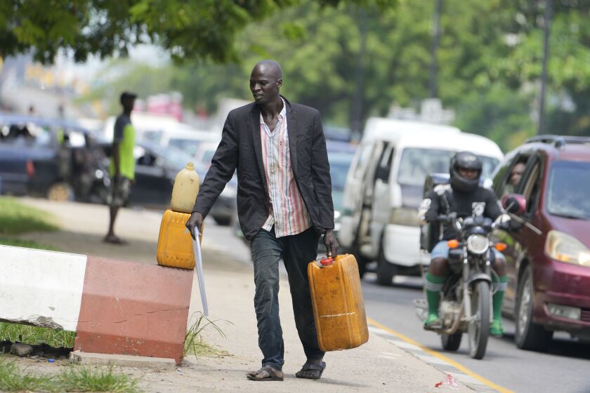 A man sells black market fuel on the street in Lagos, Nigeria, Tuesday, May 30, 2023. Nigerian President Bola Tinubu has scrapped a decadeslong government-funded subsidy that has helped reduce the price of gasoline, leading to long lines at fuel stations Tuesday as drivers scrambled to stock up before costs rise. (AP Photo/Sunday Alamba)