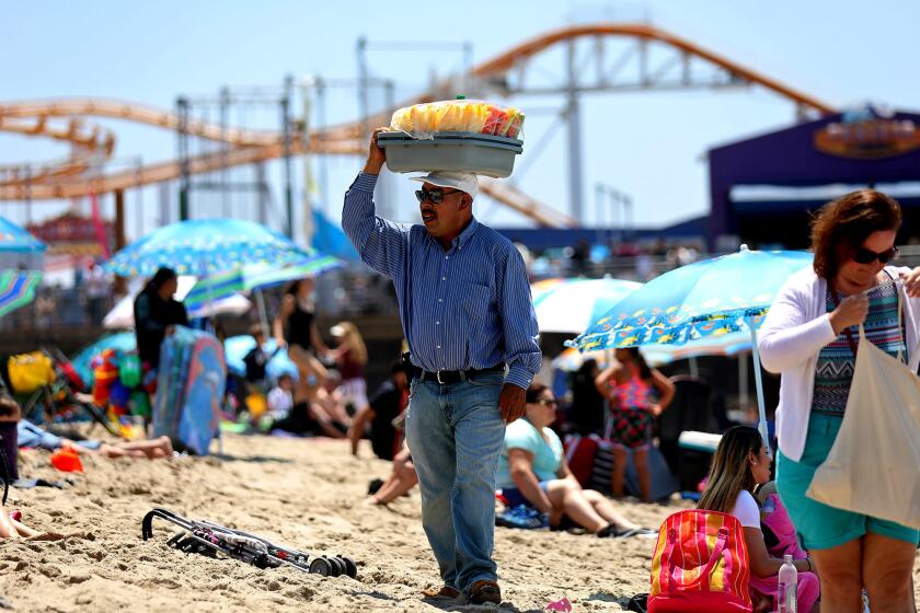 A vendor sells fruit to beachgoers in Santa Monica. Some licensed vendors working around the pier say a new ordinance that can penalize them for blocking access ways has made them nervous about being arrested.