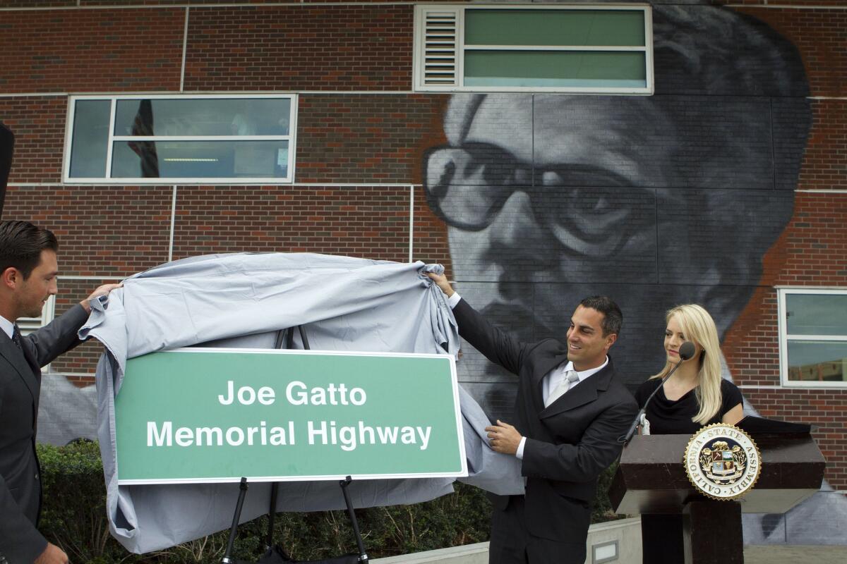 Assemblymen Ian Calderon, from left, Mike Gatto and Gatto's wife, Danielle, unveil a memorial freeway sign during the Joseph Gatto Memorial Highway Dedication Ceremony, which took place at the Los Angeles County High School for the Arts on the Cal State L.A. campus on Nov. 12, 2014.