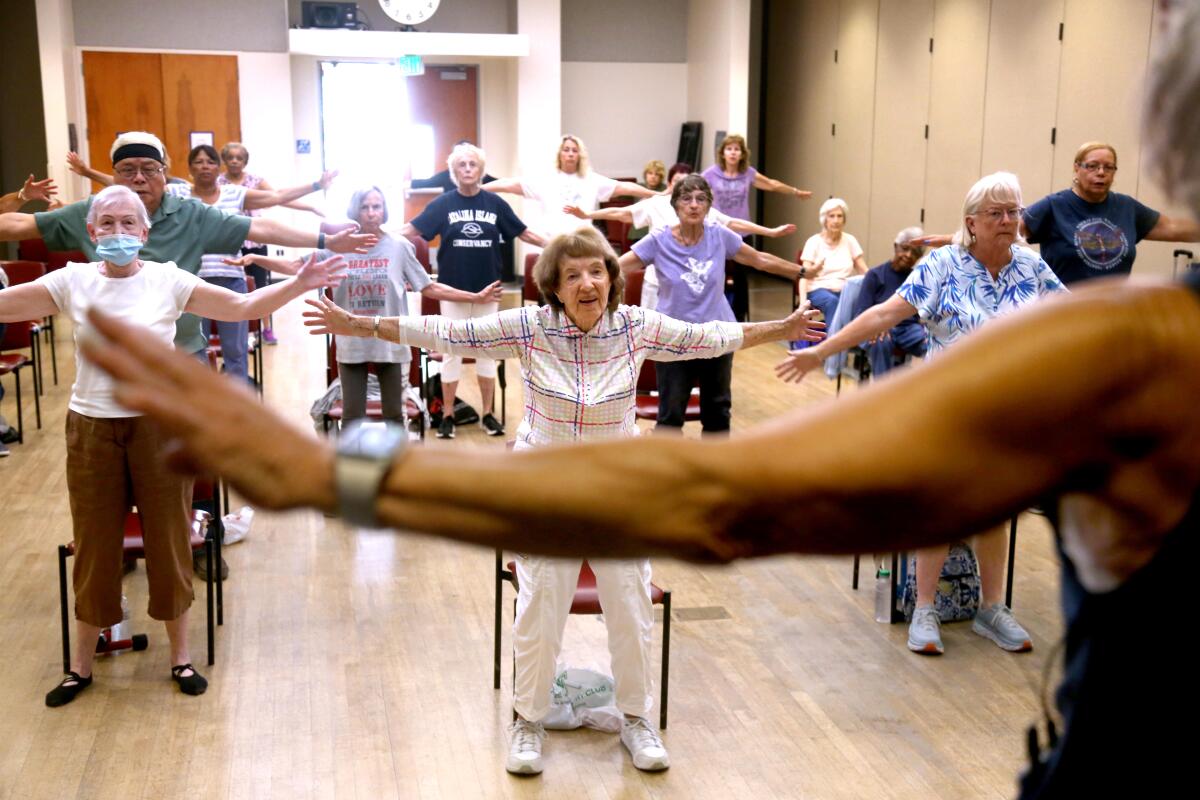 Seniors hold their arms out during a class led by Teri Lemoine, foreground