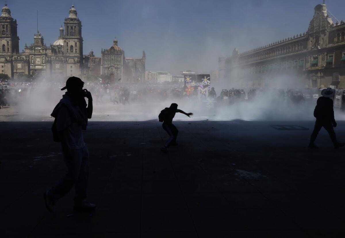 Protesters are silhouetted against fumes in Mexico City.
