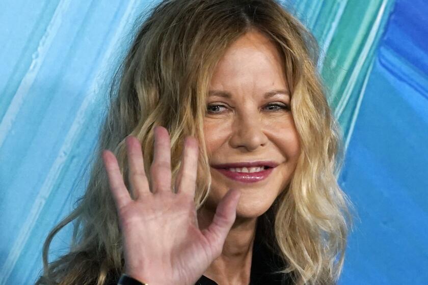 Meg Ryan waving and smiling while wearing black sequin dress at red carpet event